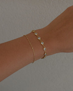 gold cubic zirconia chain bracelet stacked with a dainty minimalist style chain beaded bracelet